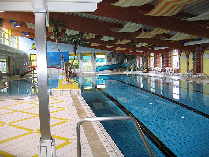 Man sieht den Innenbereich des Schwimmbades mit Schwimmerbecken auf der rechten und dem Nichtschwimmerbecken auf der linken Seite.