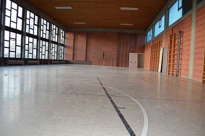 Das Bild zeigt die Sporthalle von innen. Der Boden ist mit Markierungen versehen.