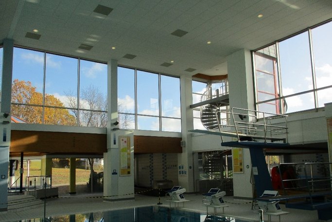 Das Bild zeigt einen Sprungturm an einem Schwimmbecken in einem Hallenbad.