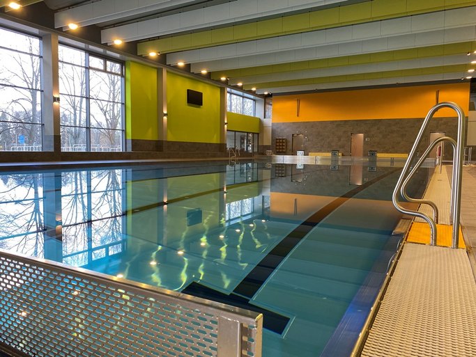 Das Bild zeigt ein Schwimmbecken in einem Hallenbad mit bunten Wänden.