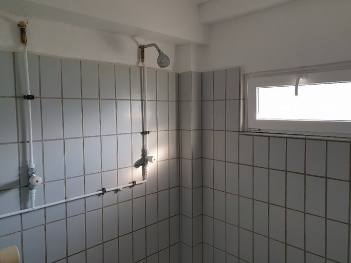 Das Bild zeigt einen gefliesten Sanitärbereich mit zwei Duschen.