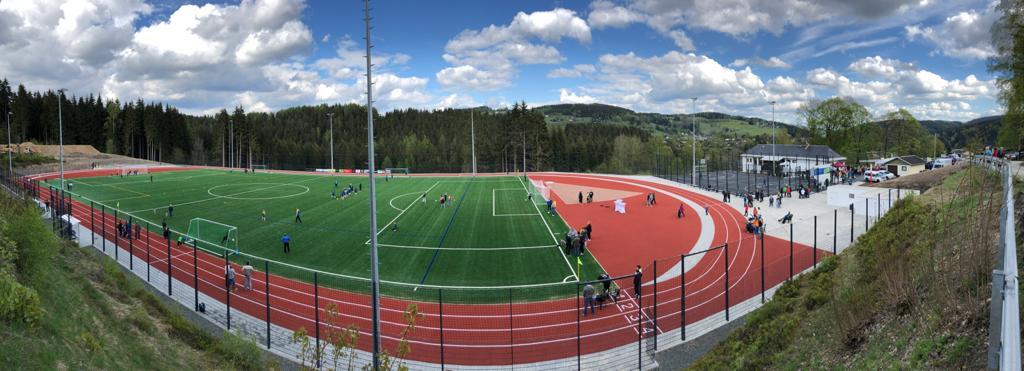 Das Bild zeigt eine Sportanlage mit roter Kreislaufbahn und Fußballfeld in der Mitte.