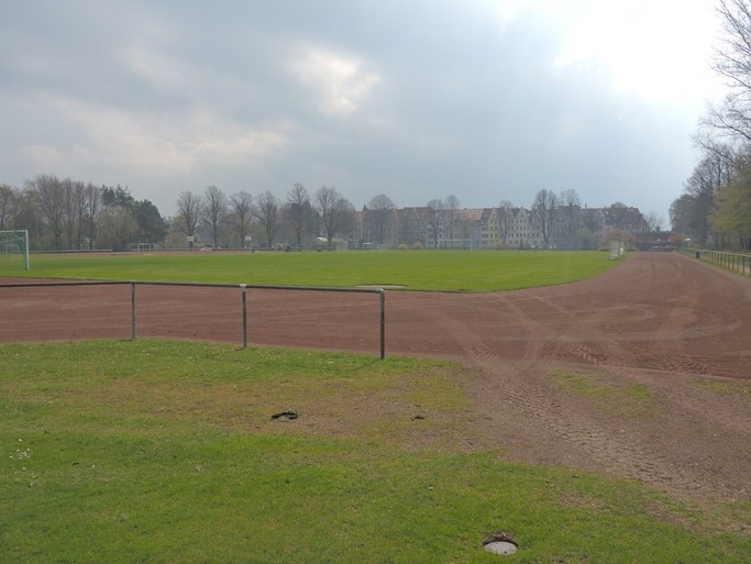 Das Bild zeigt einen Sportplatz mit Rasen- und Erdflächen.