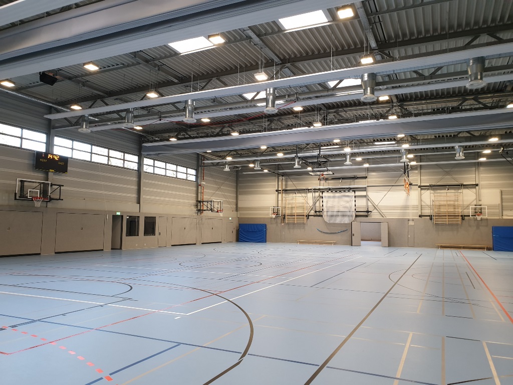 Das Bild zeigt ein hell gestaltete Sporthalle mit diversen Sportgeräten.