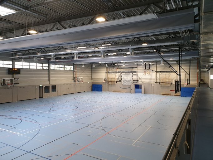 Das Bild zeigt ein hell gestaltete Sporthalle mit diversen Sportgeräten.