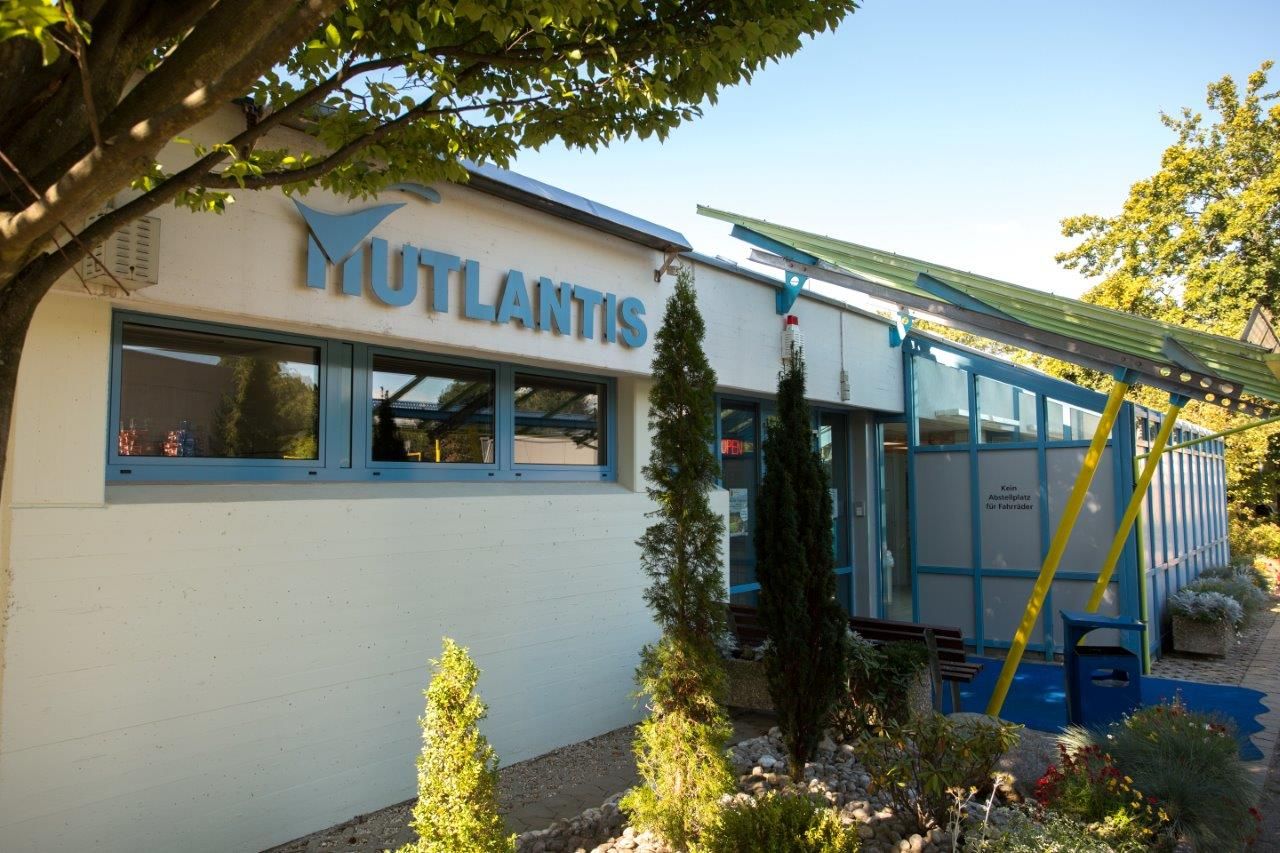 Man sieht ein Gebäude von Aussen, auf dem in großen wasserblauen Lettern das Wort "Mutlantis" steht.