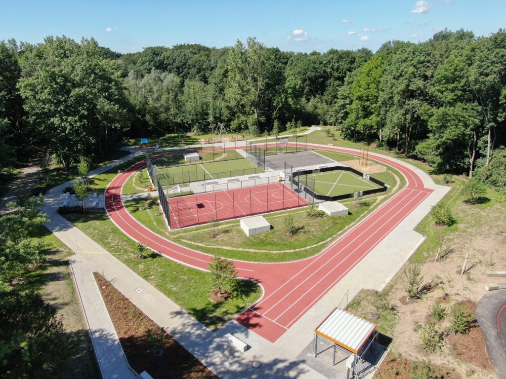 Das Bild zeigt die Luftaufnahme eines Sportplatzes, umgeben von Baumbestand.