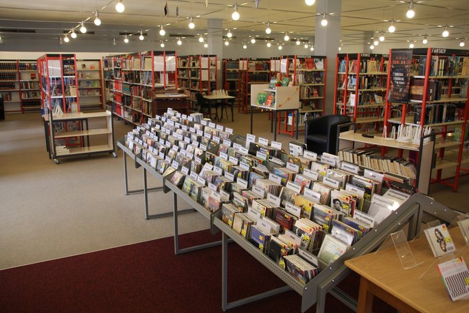 Das Bild zeigt einen Büchereiraum mit vielen roten gefüllten Bücherregalen.