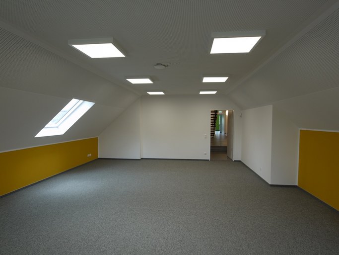 Das Bild zeigt einen leeren Dachgeschossraum mit gelben Wänden.