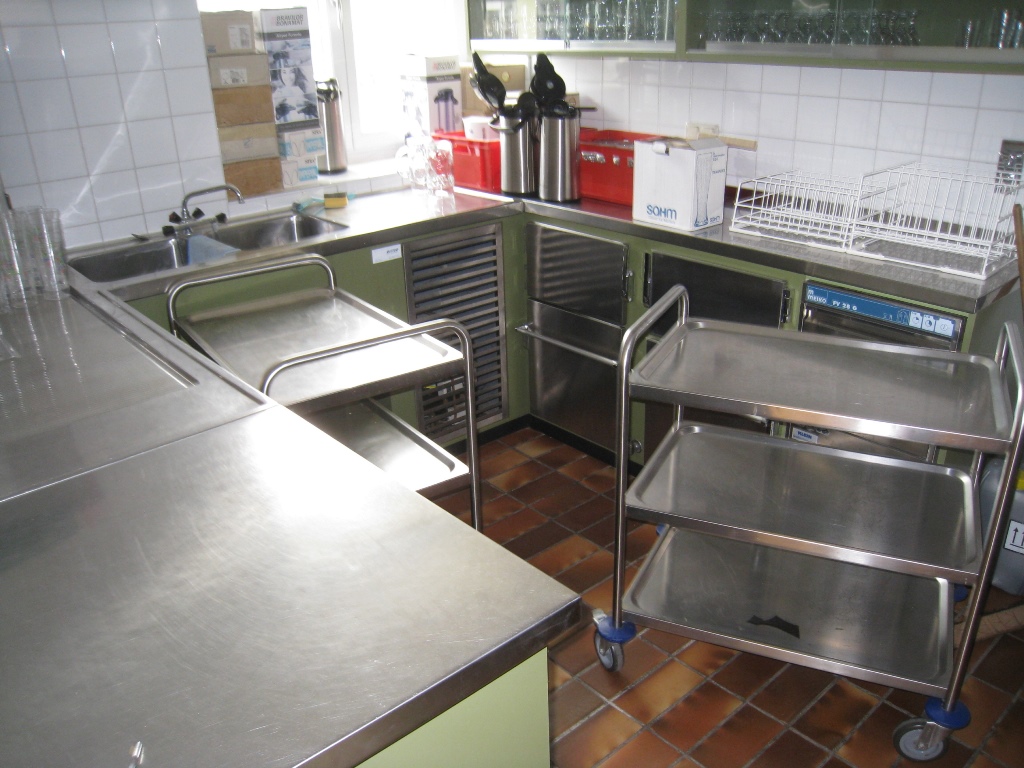 Man sieht eine Küche mit Edelstahloberflächen und Küchenutensilien wie einem Kaffeekocher.