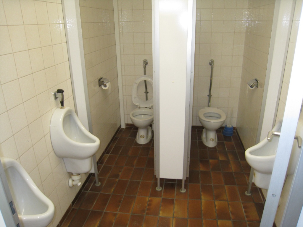 Man sieht eine Toilette mit drei Urinalen und zwei Standtoiletten.