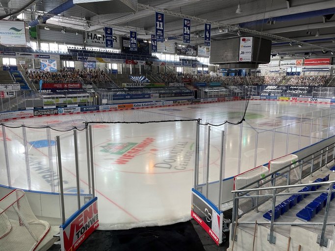 Das Bild zeigt eine Eisfläche und Zuschauerränge in einer Eishalle.