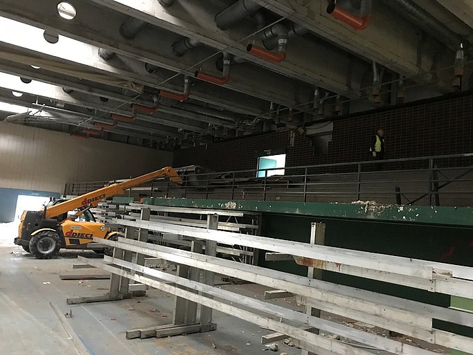 Das Bild zeigt eine Halle von innen. Eine neue Tribüne wird angebracht. Ein kleiner Kran befindet sich im hinteren Teil.