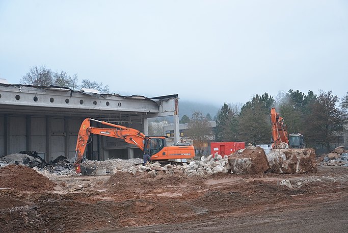 Das Bild zeigt eine Baustelle. Zwei Bagger entfernen Bauschutt vor einem Gebäude.