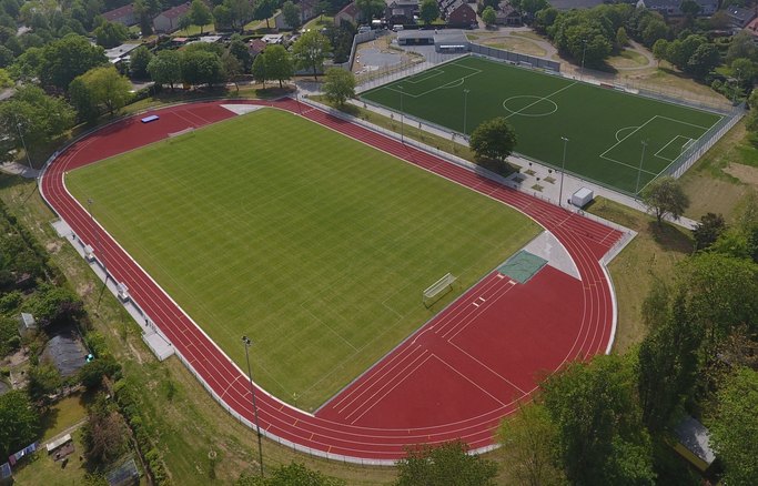 Das Bild zeigt die Luftansicht einer Sportablage mit zwei Fußballfeldern und einer umschließenden Laufbahn.
