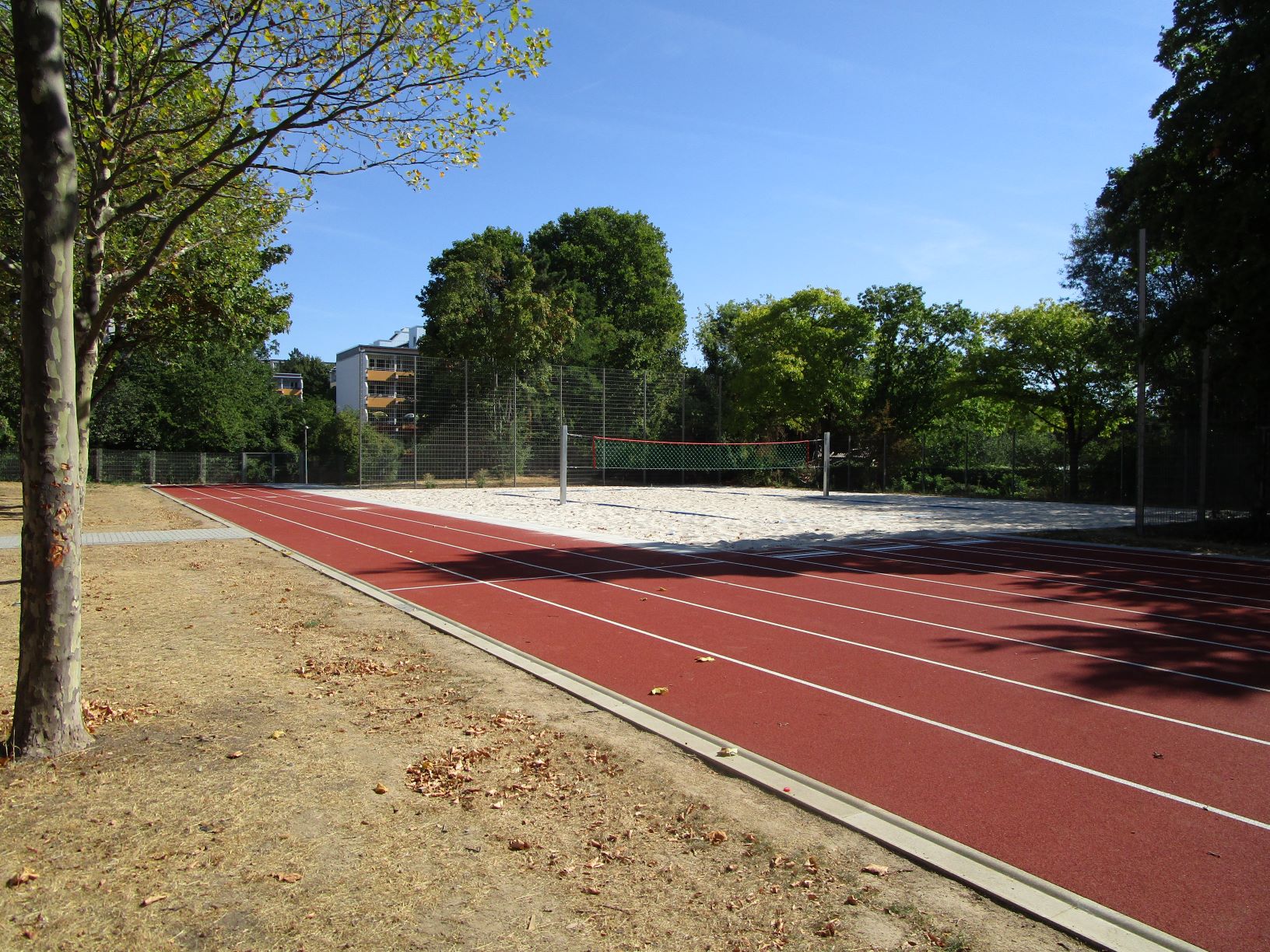 Das Bild zeigt die fertig sanierte Laufbahn und Beach-Volleyball-Feld.