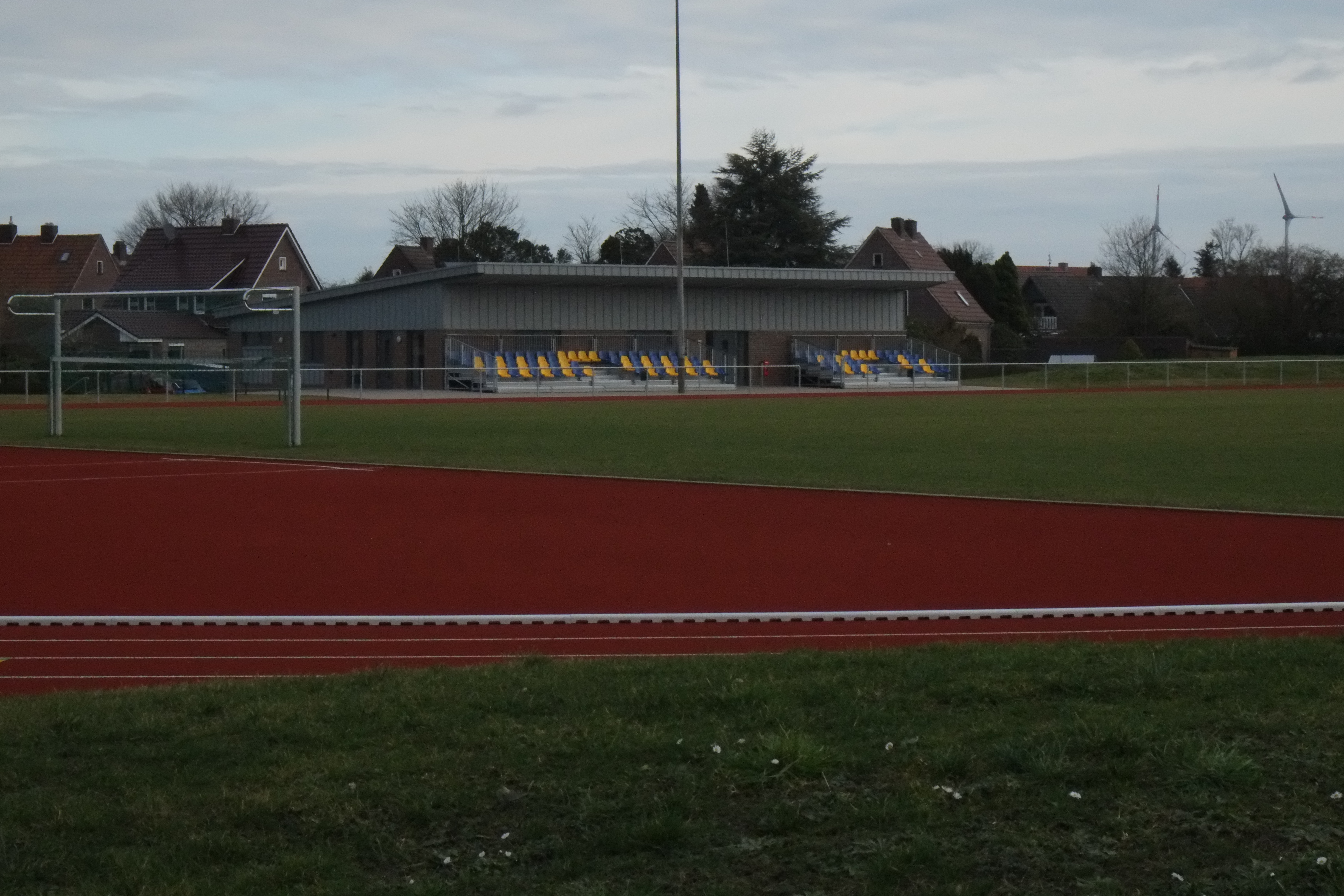 Das Bild zeigt einen Sportplatz mit Fußballplatz, Tor und Zuschauertribüne.