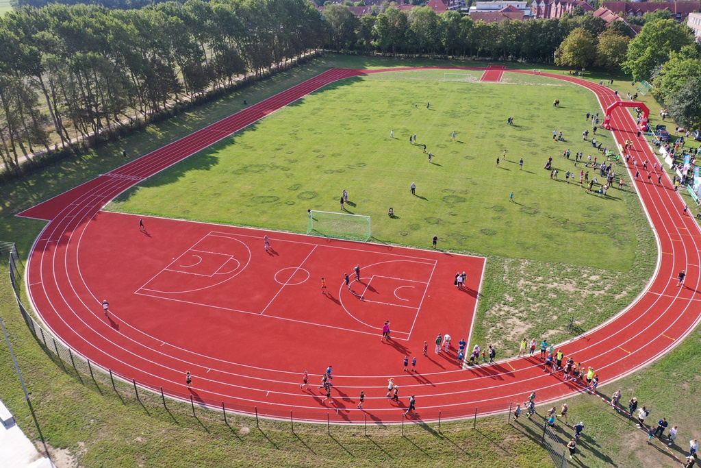 Das Bild zeigt eine Luftaufnahme von einer Sportanlage, auf der viele Menschen zu sehen sind.  