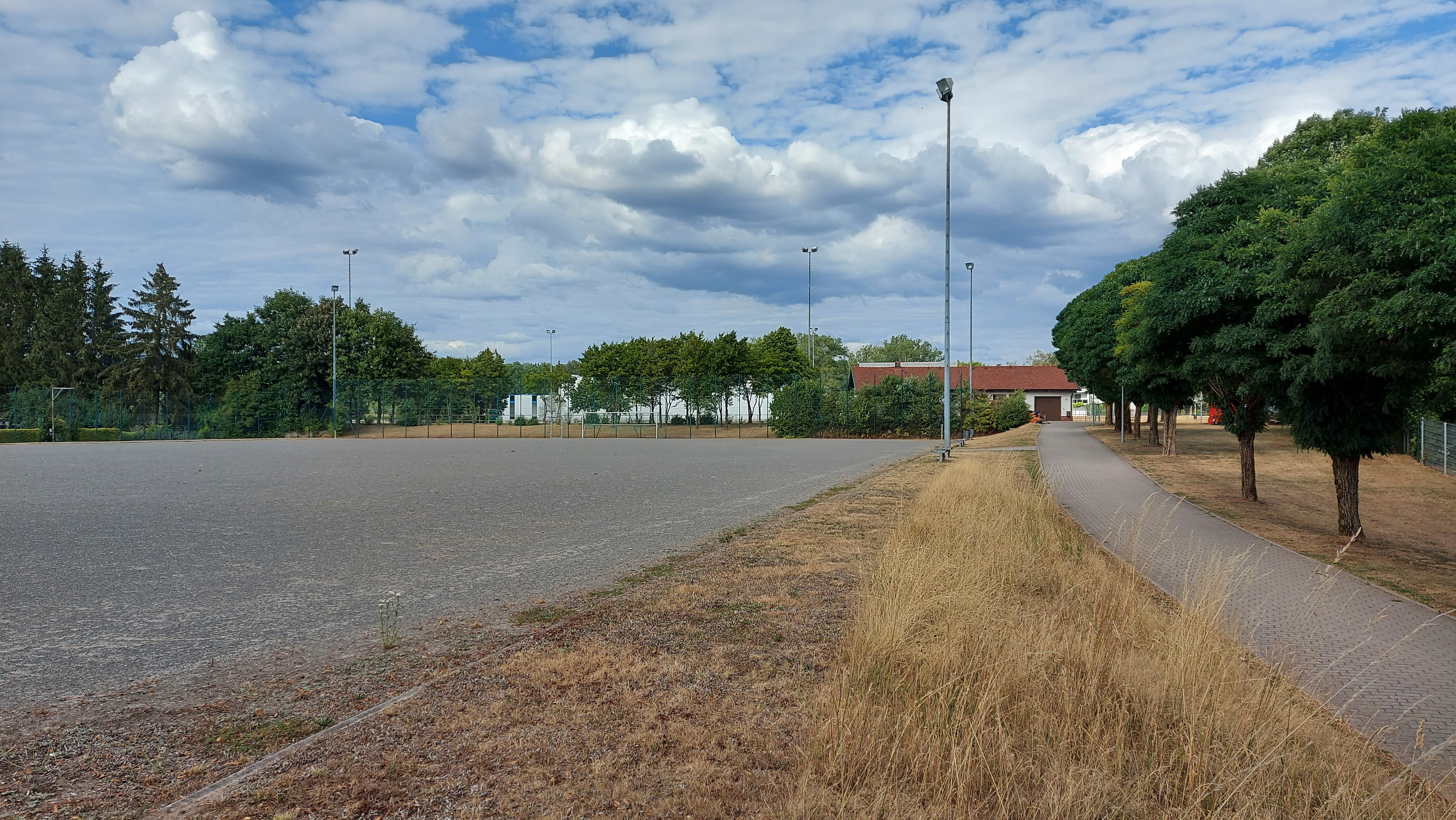 Auf dem Bild ist die Zufahrtsstraße zu einem Tennenplatz zu sehen. 